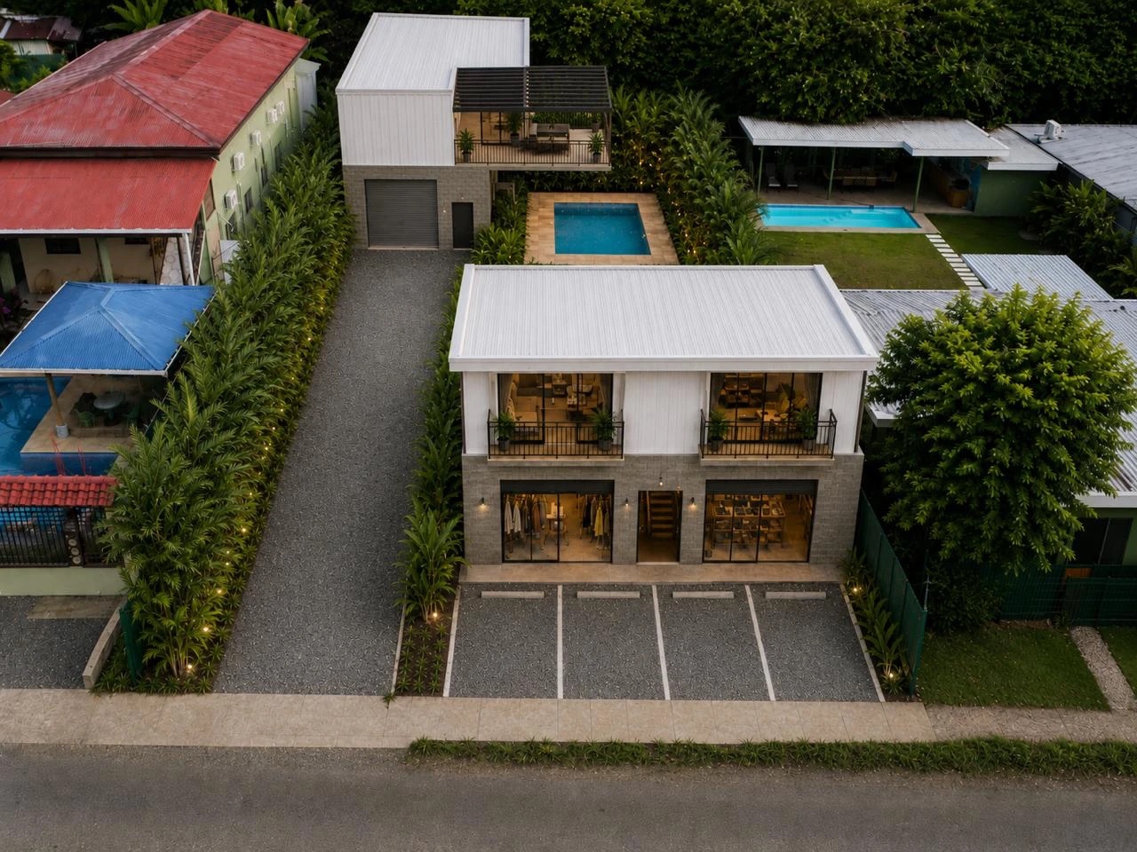 Aerial render of the SúperFreaky lot: a two-story glass-front building on the road, a workshop building at the rear, and a pool and planted patio between them.